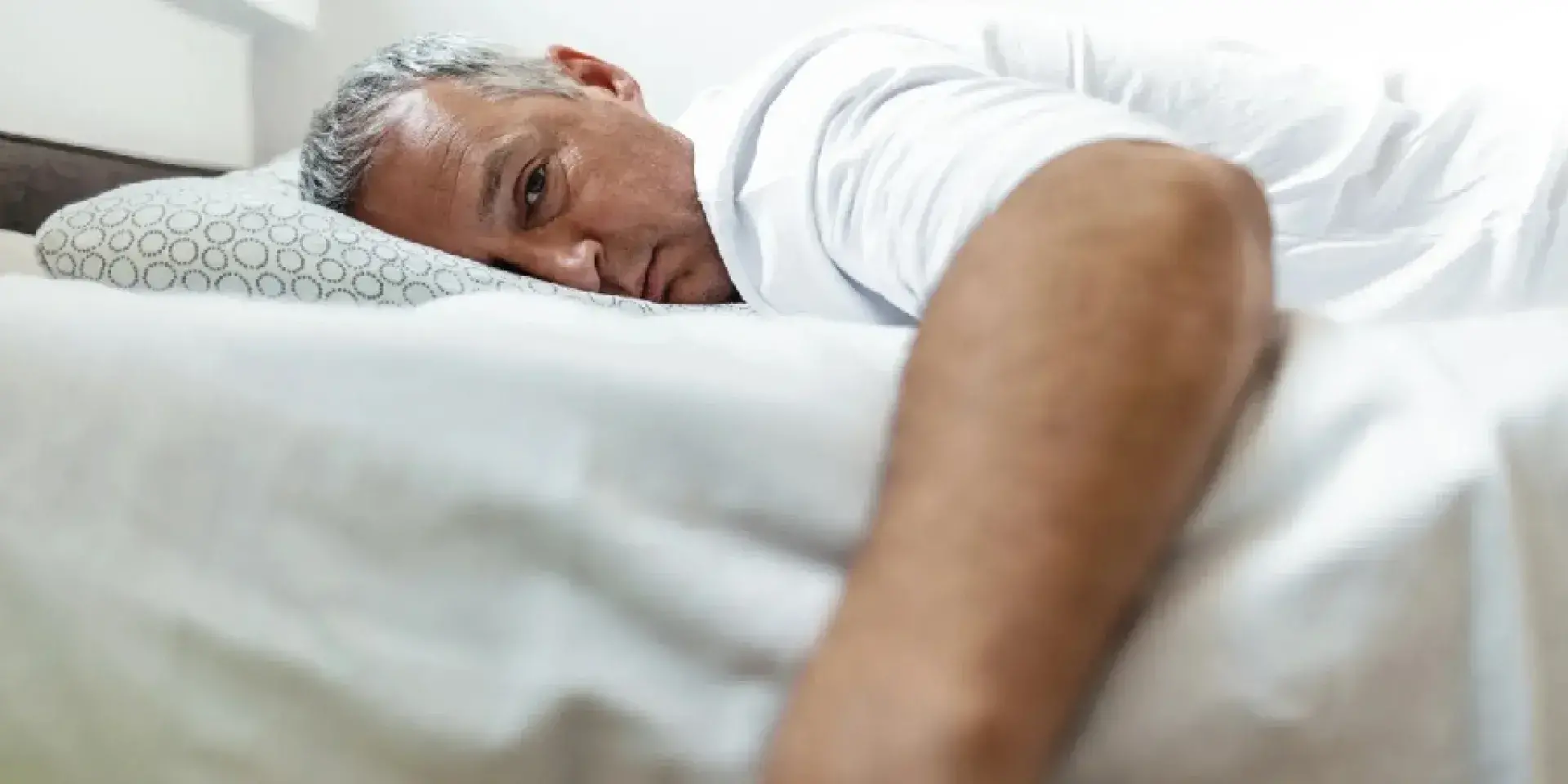 Middle aged man lying in bed