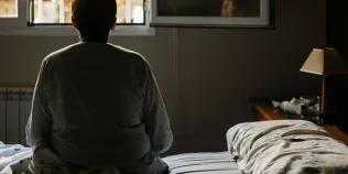 Back of person sitting on a bed looking out of a window