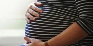 Close up of woman in stiped top cradling pregnant belly