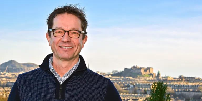 Head shot of Professor Joris Veltman against Edinburgh skyline