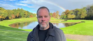 Head shot of Colin Semple with parkland and rainbow in background