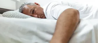 Middle aged man lying in bed