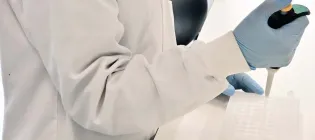 Person in lab coat using pipette