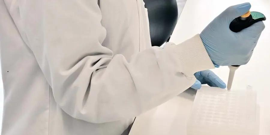 Person in lab coat using pipette